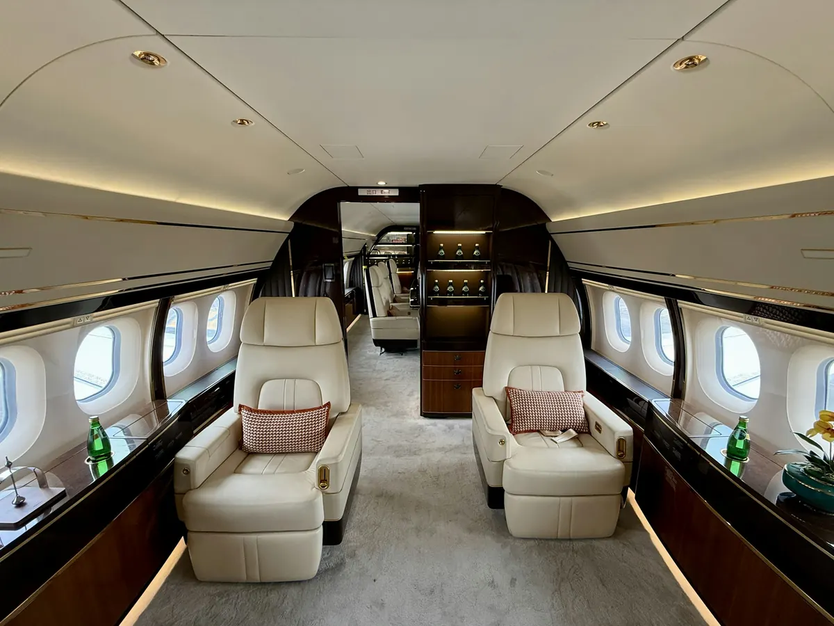 Wide cabin of a large private jet with club seats and a galley at the rear
