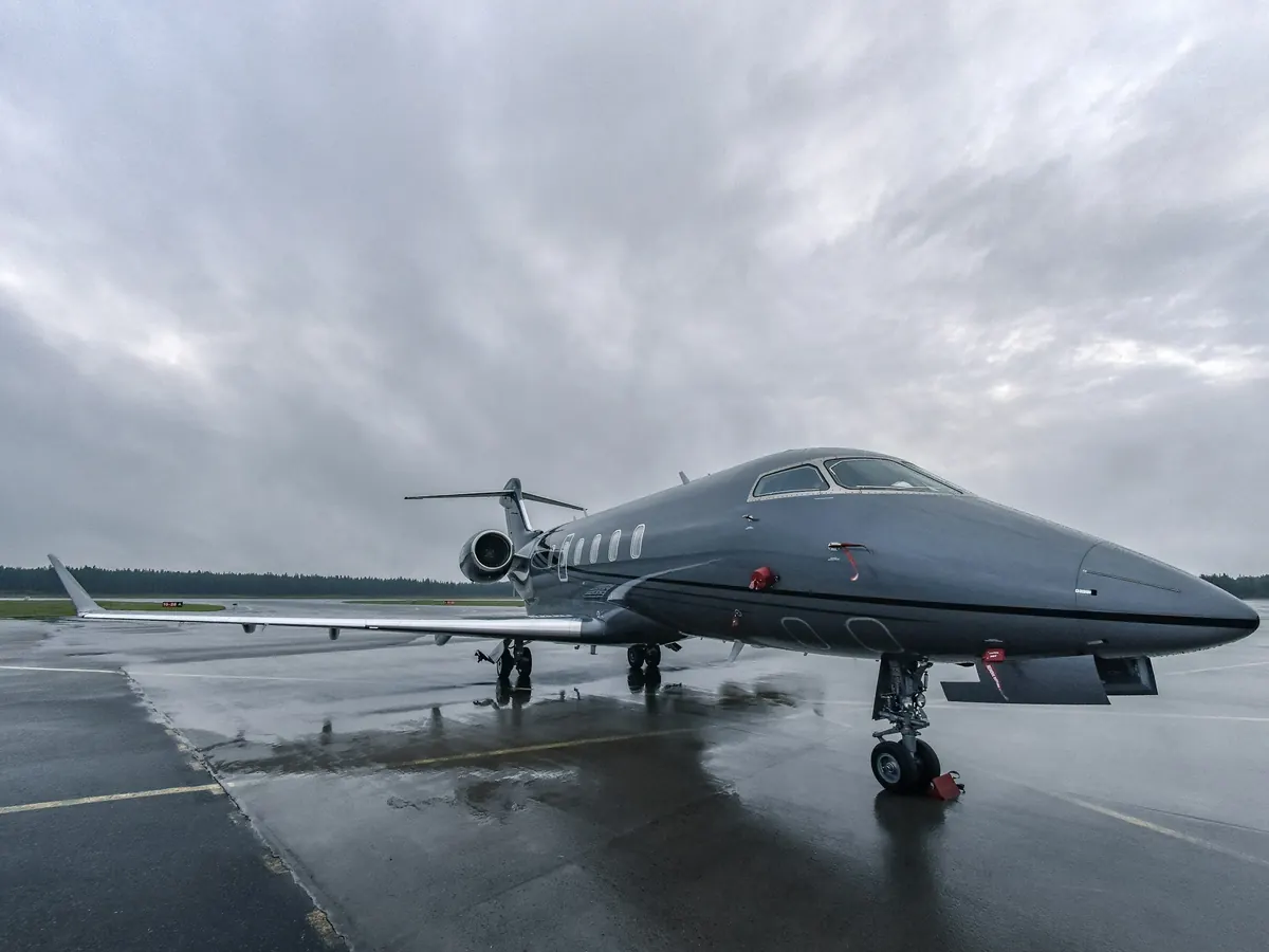 Light business jet parked on a wet ramp under grey skies