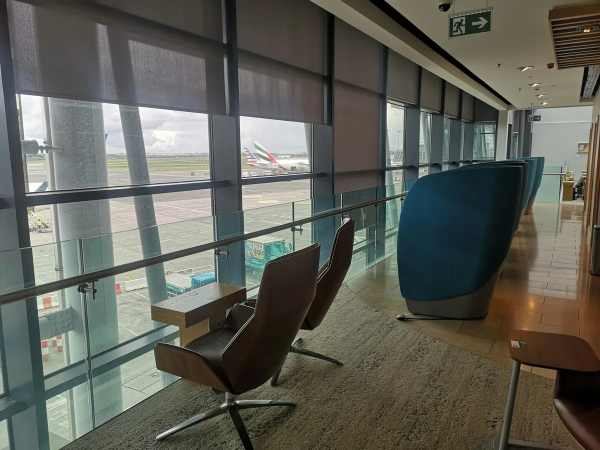 Airport lounge with leather chairs and tall windows facing the apron